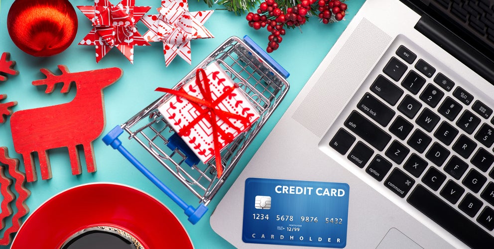 holiday items and a credit card surrounding a laptop