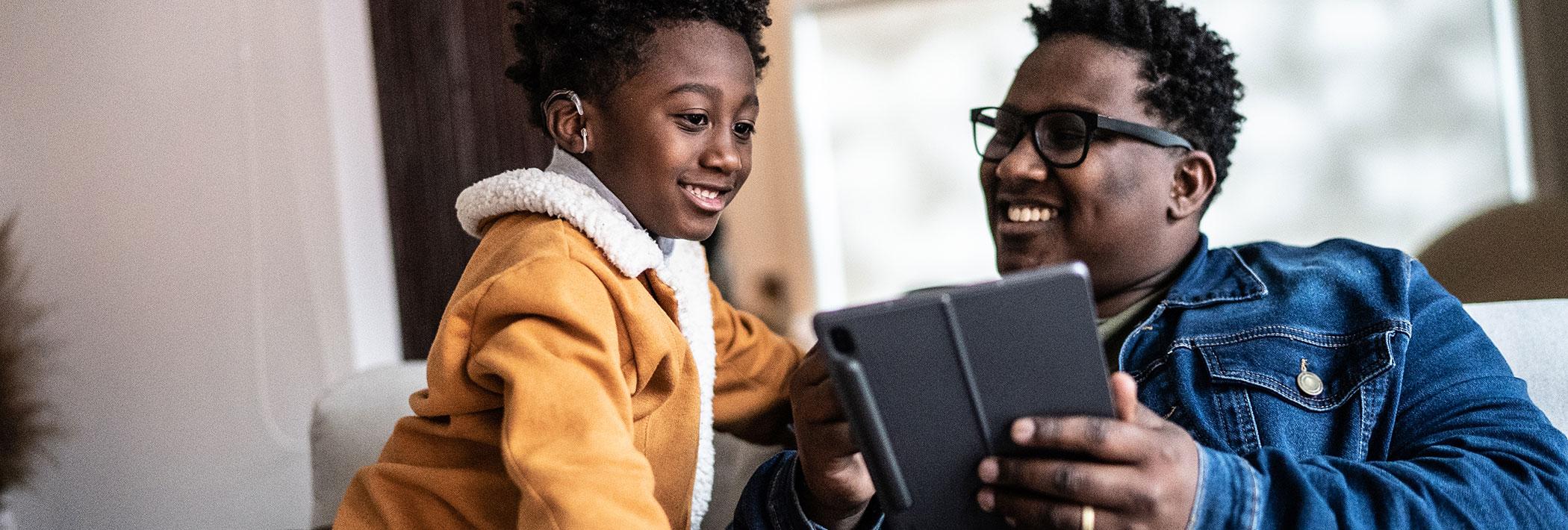 A father and son bond with each other over a tablet.