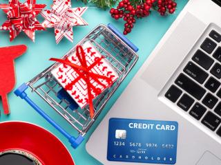 holiday items and a credit card surrounding a laptop